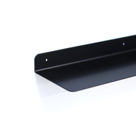 Slim metal floating shelf mounted on a wall with decor