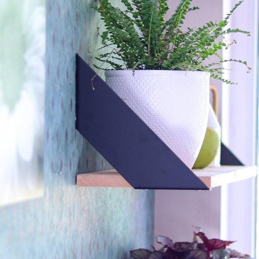 Metal shelf brackets supporting a wooden shelf on a wall