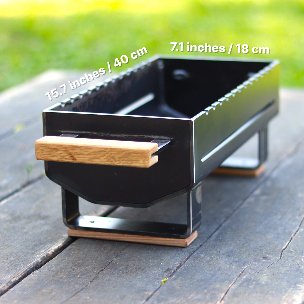 Black grill with wooden handle on a wooden surface, measurements displayed.