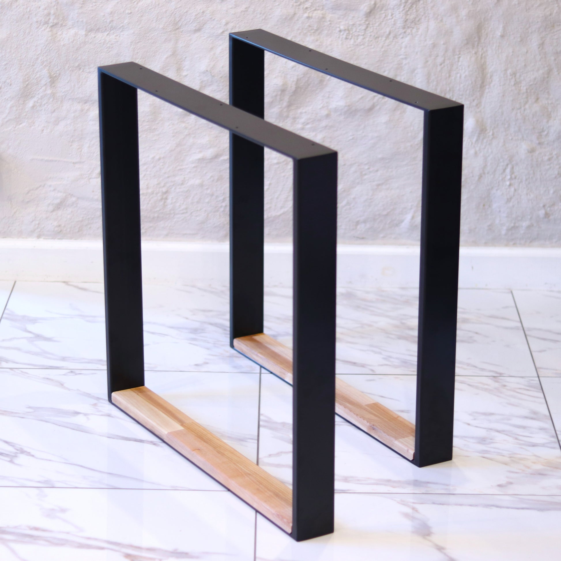 Black metal table legs with a wooden base on a light marble floor