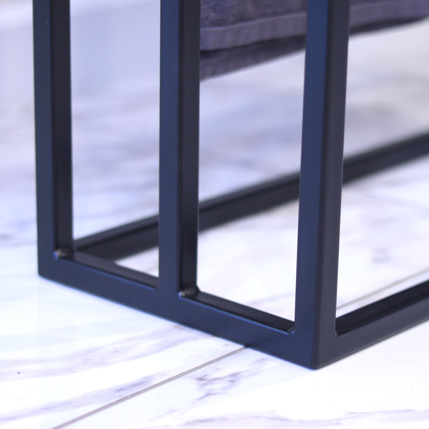 Black towel rack with towels draped over the bars