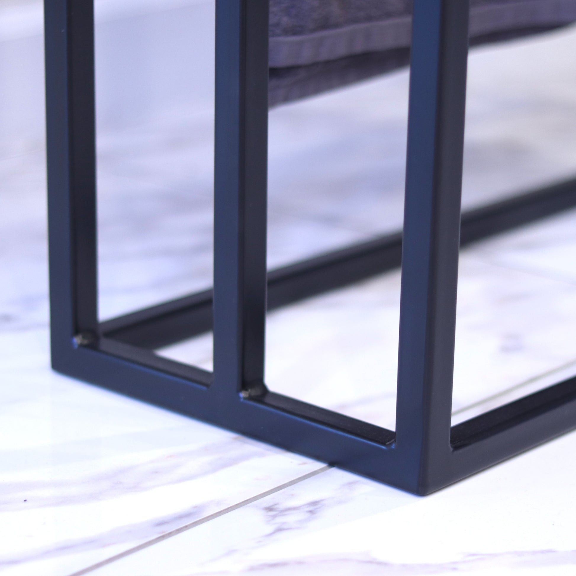 Black towel rack with towels draped over the bars